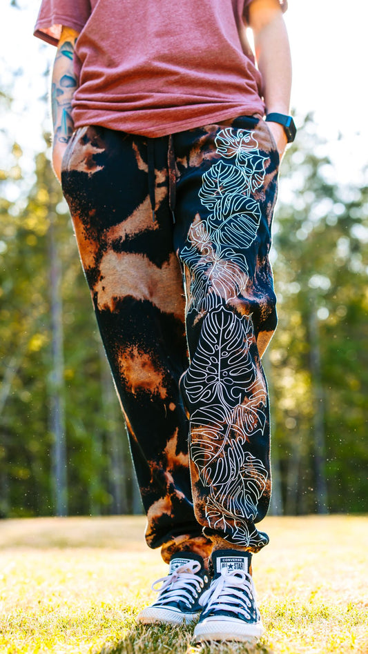 Bleached Jogger Style Sweatpants with Monstera leaves climbing up the leg by RattTrap Artistry