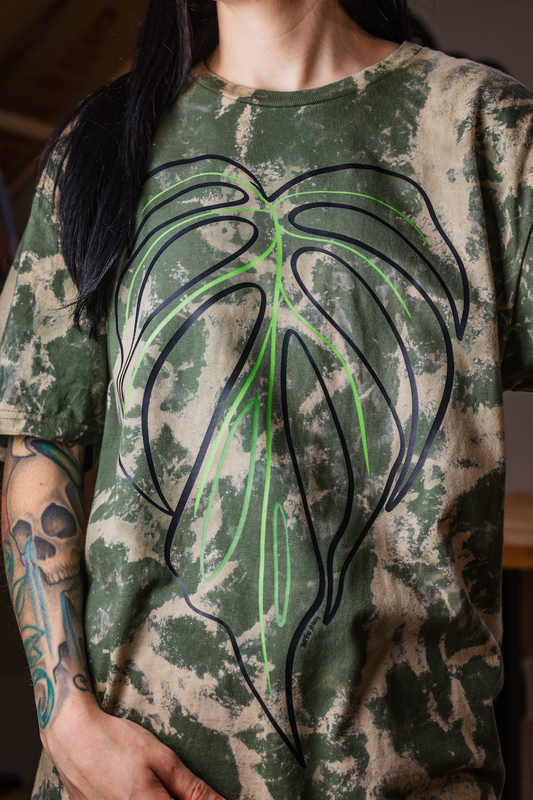 T-shirt with a black and green leaf design on a bleached background